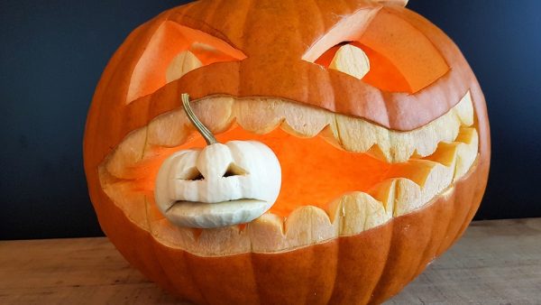 A pumpkin with a small pumpkin in its mouth