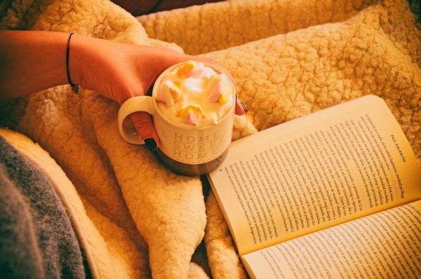 A woman reading a book with a mug of hot chocolate