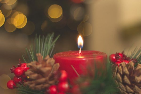 A red candle surrounded by a pine wreath