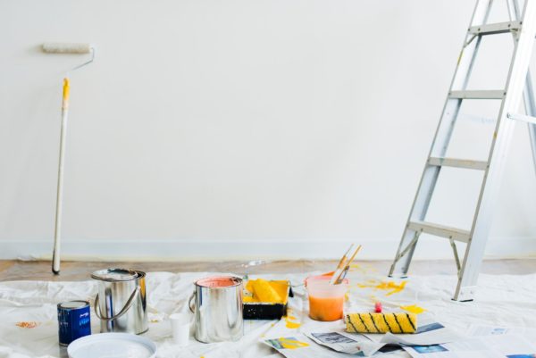 A ladder and buckets of paint in a white room